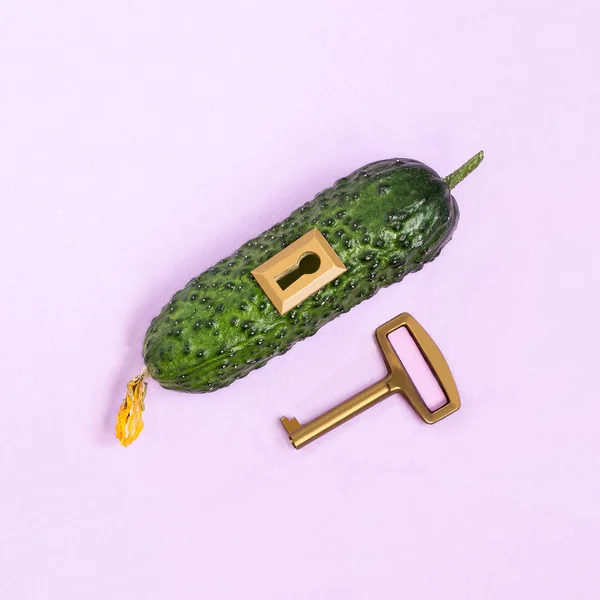 Fresh cucumber with lock and key on pastel lilac background. Minimal style. Creative idea, imagination and fantasy. Original food concept: key to diet and healthy eating
