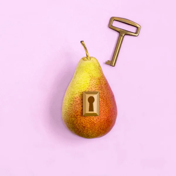 Ripe pear with lock and key on pastel lilac background. Minimal style. Creative idea, imagination and fantasy. Original food concept: key to diet and healthy eating