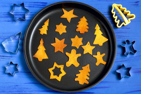 Child making decorations of orange peel for Christmas. Children\'s art project. DIY concept. Step by step photo instruction. Step 5. Dry completely on baking sheet