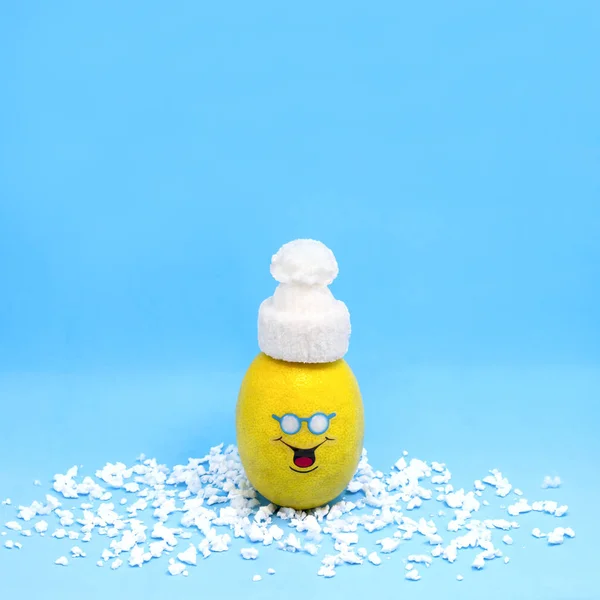 Lemon in form of funny little man in white knitted hat. Creative concept: preservation of fruits and vegetables in winter. Minimal style