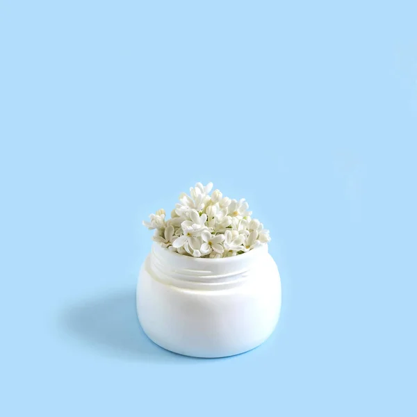 Frasco com flores de lilás branco como creme cosmético — Fotografia de Stock