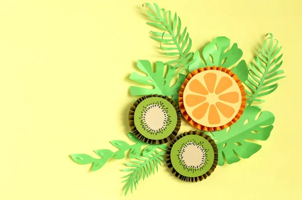 Fatias de papel de kiwi e laranja com papel folhas tropicais — Fotografia de Stock