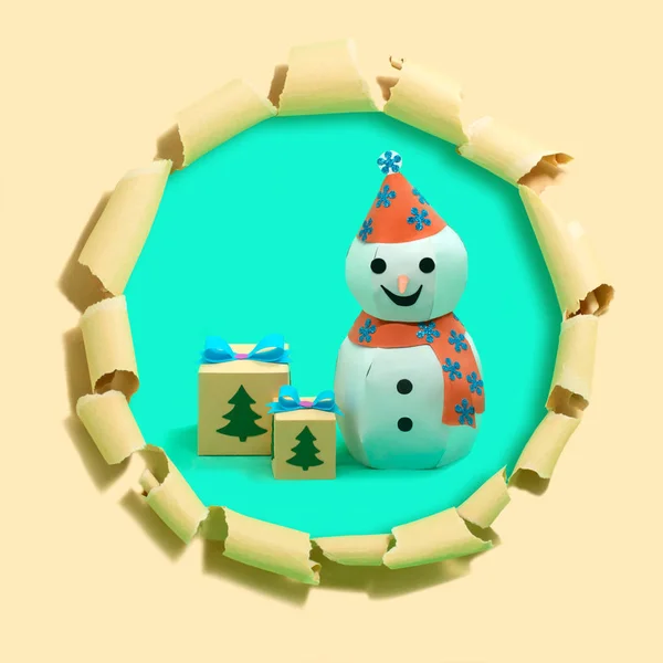 Paper snowman and Christmas gift boxes on torn paper with hole