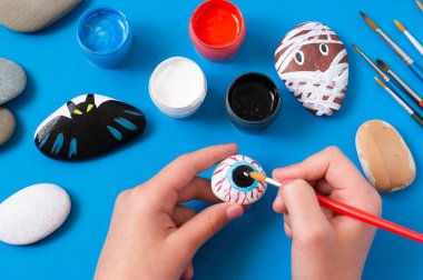 Cadılar Bayramı karakterlerine taş çizmek. Çocuklar için sanat projesi. Diy konsepti. Cadılar Bayramı partisi dekoru. Deniz taşına çizilmiş göz 