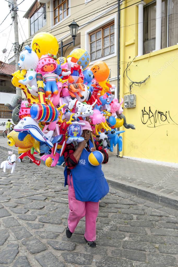 Una señora que vende juguetes de plástico camina por una calle de