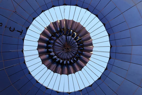 A hot air balloon begins to deflate after the canopy of the balloon is opened to allow the hot air within the balloon to escape.