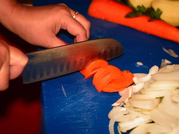 Bir kesme tahtası üzerinde bir şefin bıçak ile kesme havuç