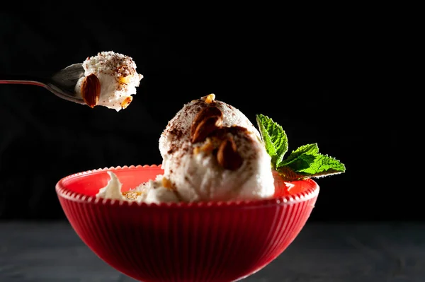 spoon with ice cream on a black background, ice cream summer mood cool. Ice cream white promsemin with mint and chocolate. Ice cream on pink cup