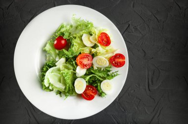 Kilo vermek ve sağlıklı beslenmek için diyet salatası, sağlıklı yaşam tarzı ve doğru yemekler, sebzeli salata kiraz domatesleri ve bıldırcın yumurtaları, düz yatak ve gri arka planda üst görünüm.