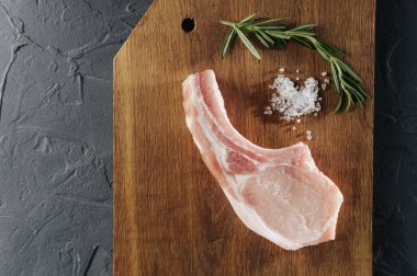 Ahşap bir tahtada pirzola ve çiğ biftek ile birlikte pişirme ve tuz, yukarıdan manzara, düz yatış ve üst görünüm