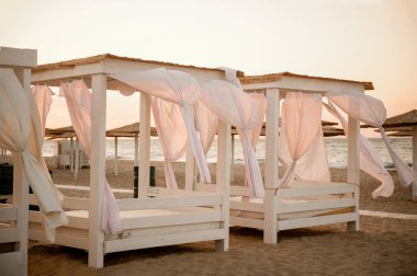 a few gazebos on the beach at sunset with evolving curtains, without people clipart