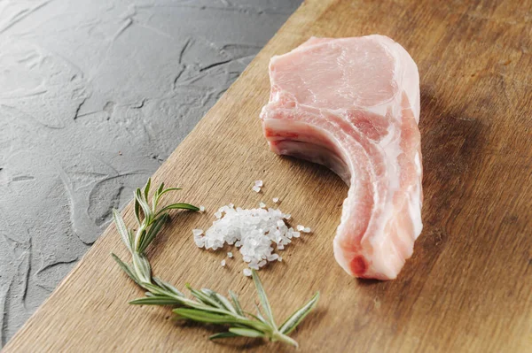 Carne cruda con sal extendida y croome en una vista de tablero de madera desde el lado — Foto de Stock