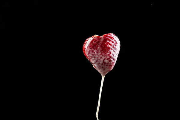 Fresas en un palo, crema con fresas sobre un fondo oscuro aislado — Foto de Stock