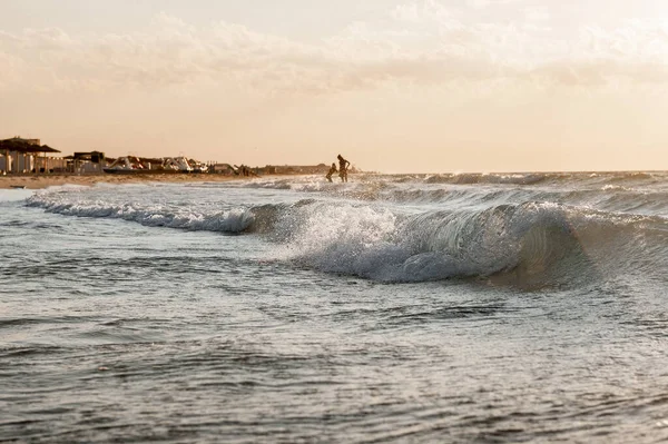 Pôr do sol no mar no fundo as pessoas tomam banho e alegram-se, descansam no mar — Fotografia de Stock