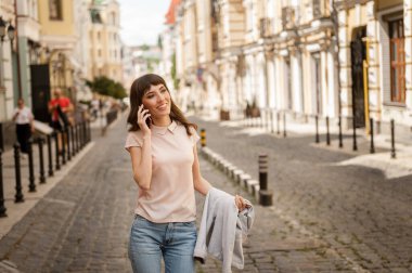 Tatlı kız şehirde tek başına dolaşıyor, telefonda konuşuyor.