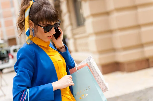 Shopaholic girl talking on the phone stands on the street — Stock Photo, Image