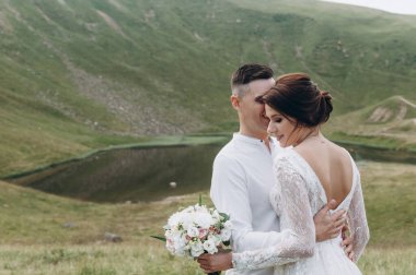 Gelin ve damat, altın tepede durarak birbirlerine nazikçe sarılıyorlar..