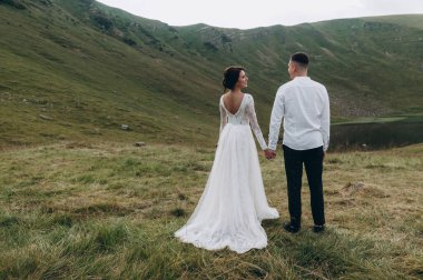 Manzaralı dağ manzarası. Genç ve güzel bir çift damat ve gelin dağda yürüyor.