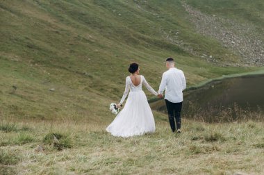 Manzaralı dağ manzarası. Genç ve güzel bir çift damat ve gelin dağda yürüyor.