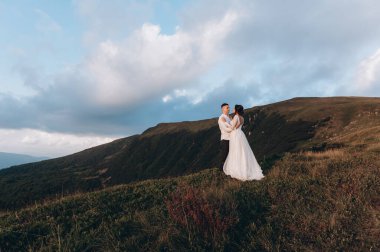 Manzaralı dağ manzarası. Genç ve güzel bir çift damat ve gelin dağda yürüyor.