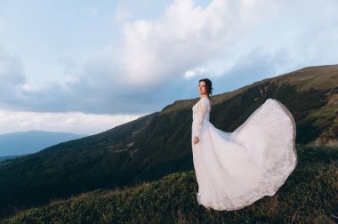 Gelini gezdir. Hafif ve havadar bir elbise rüzgarda dalgalanıyor..