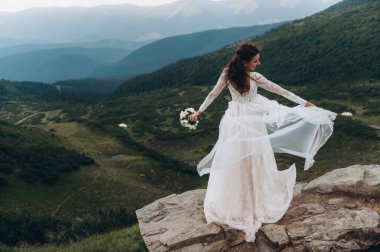 Gelini gezdir. Hafif ve havadar bir elbise rüzgarda dalgalanıyor..