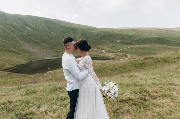 Gelin ve damat, dağlarda bir göl kenarında dururlar.