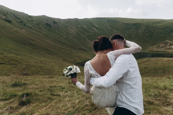 Gelin ve damat, altın tepede durarak birbirlerine nazikçe sarılıyorlar..