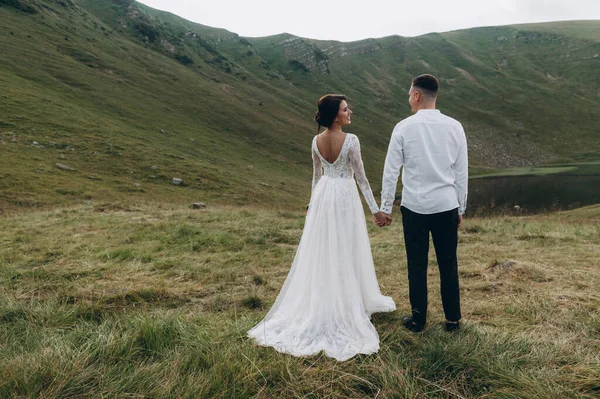 Manzaralı dağ manzarası. Genç ve güzel bir çift damat ve gelin dağda yürüyor.