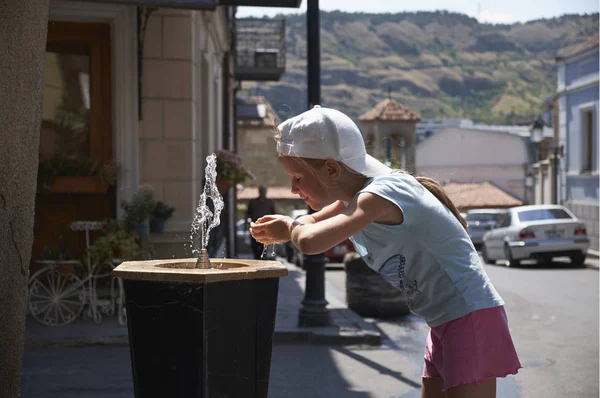 Милая девочка, пьющая воду из фонтана летом Стоковое Фото