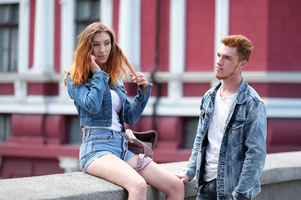 Een rood harige jongen is wachten voor een rood harige meisje praten op haar mobiele telefoon — Stockfoto