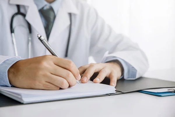 Closeup of male doctor's hands taking notes or fills in the clie — Stock Photo, Image