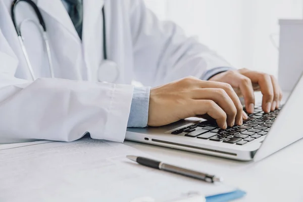 Close up of male doctor typing on laptop computer while sitting — Stock Photo, Image
