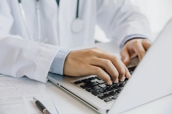Close up of male doctor typing on laptop computer while sitting — Stock Photo, Image