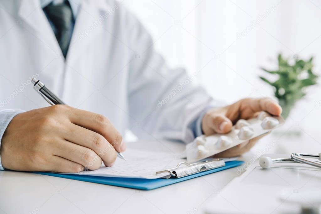 Close up hands doctor take pills, tablets and writing prescripti