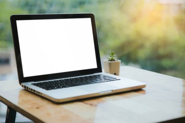 ahşap masa üzerinde laptop ve yeşil bitki