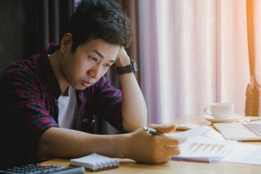 Stresli adam. Genç bir adam masasına oturur ve ellerini tutar