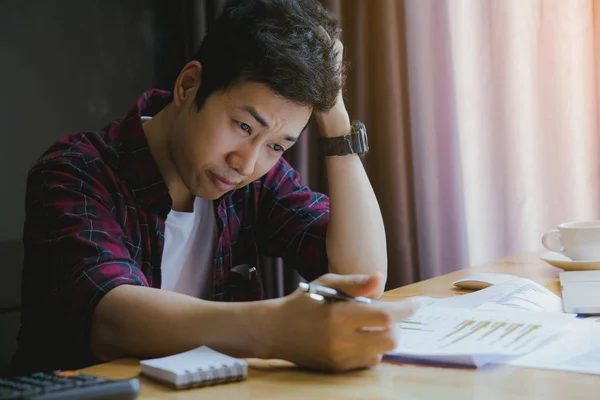 Stressad man. En ung man sitter vid sitt skrivbord och håller händerna på — Stockfoto