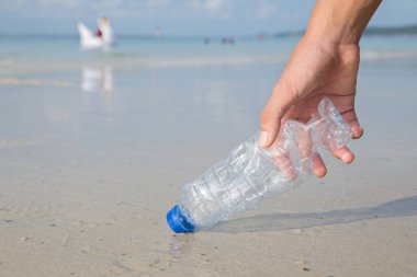 Sahilde plastik şişe temizliği alma eli.
