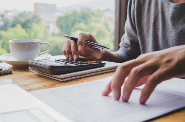 Genç İş adamı bir calculato kullanarak masa ofisi üzerinde çalışıyor