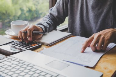 Genç İş adamı bir calculato kullanarak masa ofisi üzerinde çalışıyor