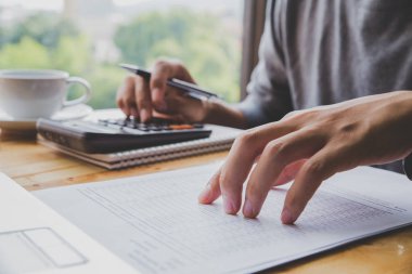Genç İş adamı bir calculato kullanarak masa ofisi üzerinde çalışıyor