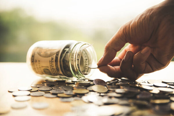 close up hand putting coin into glass bottle.Business, finance, 