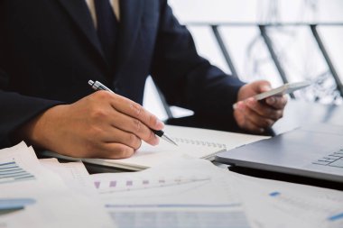 İşadamı elinde cep telefonu ve defterine yazıyor. Gebe