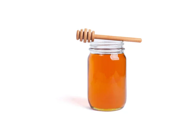 Glass jar full of honey with a wooden dipper on top — Stock Photo, Image