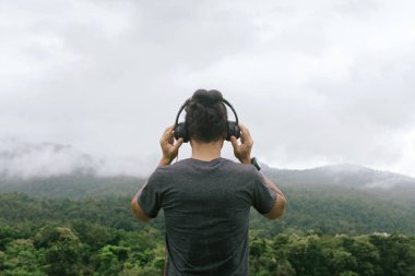 Kulaklıkları tutan adam elleri arkada. mesafeye bakar 