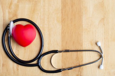 Tahta masada kırmızı kalp ve stetoskop. Duymak için doktor aracı