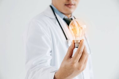 Beyaz önlüklü ve stetoskoplu doktor, elinde ampul. Bu, 