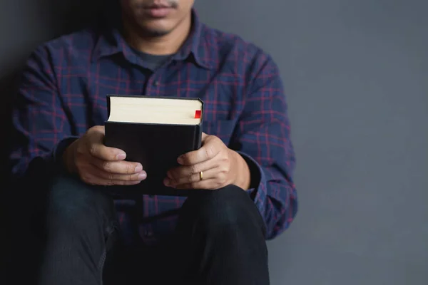 Mann sitzt und hält eine Bibel, betet, Männer. — Stockfoto