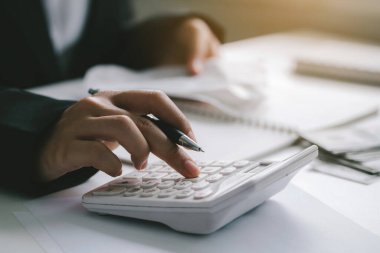  İş adamı ya da muhasebecinin el ele tutuşma kalemini kapatın. Hesap makinesi üzerinde çalışarak iş verilerini ve mali muhasebe kavramını hesaplayın.